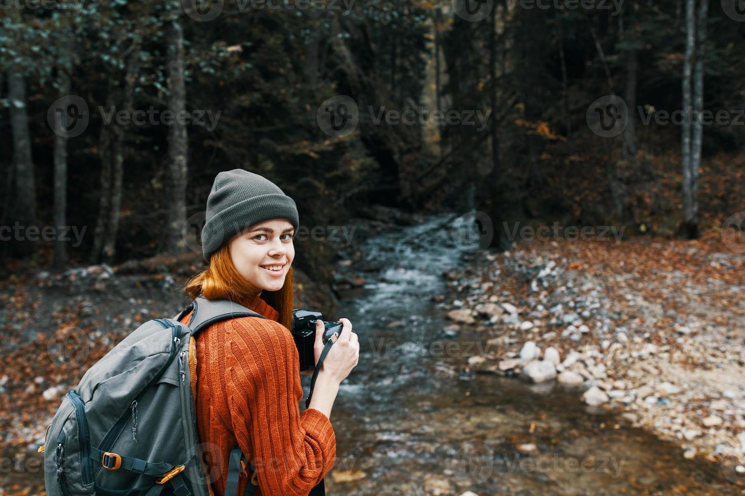 femme avec une caméra sur la nature dans le montagnes près le rivière côté vue photo
