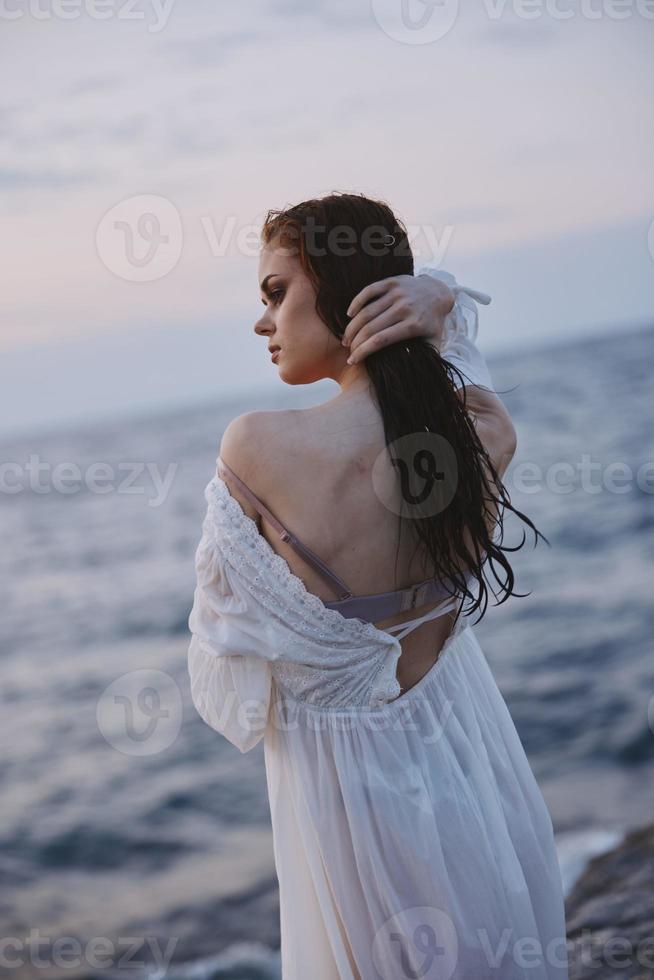 femme dans blanc robe avec humide cheveux par le océan photo