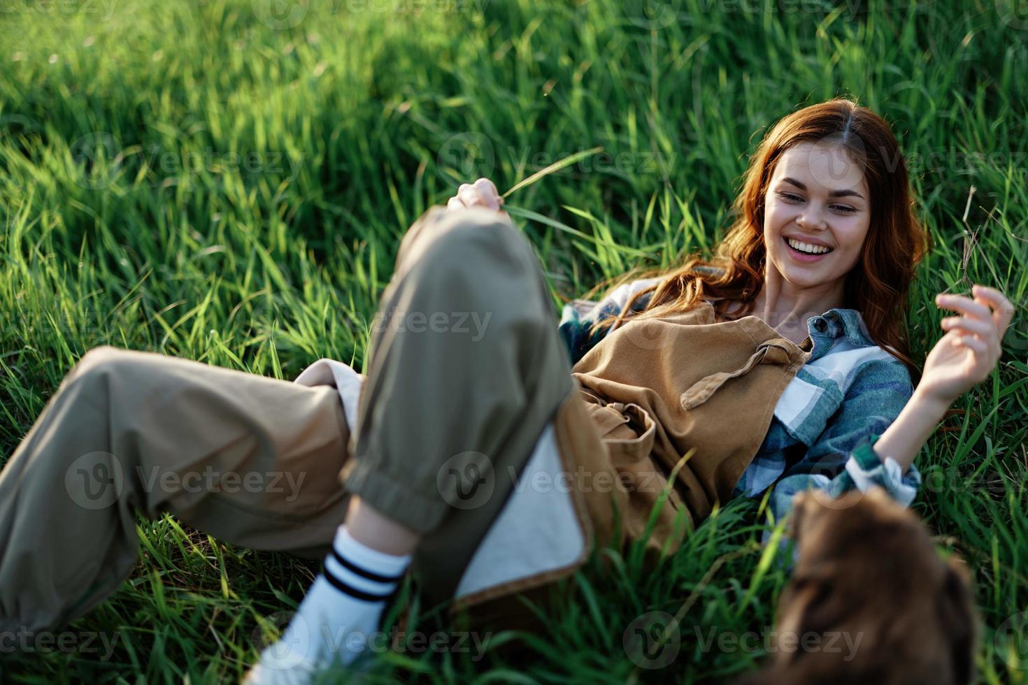 femme Jeu avec sa chien dans la nature souriant et mensonge sur le vert herbe dans le parc, content en bonne santé relation entre maîtresse et animal de compagnie photo