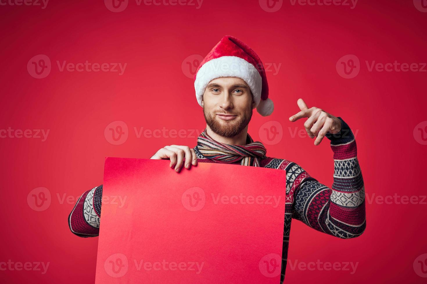 émotif homme dans une Père Noël chapeau en portant une bannière vacances rouge Contexte photo