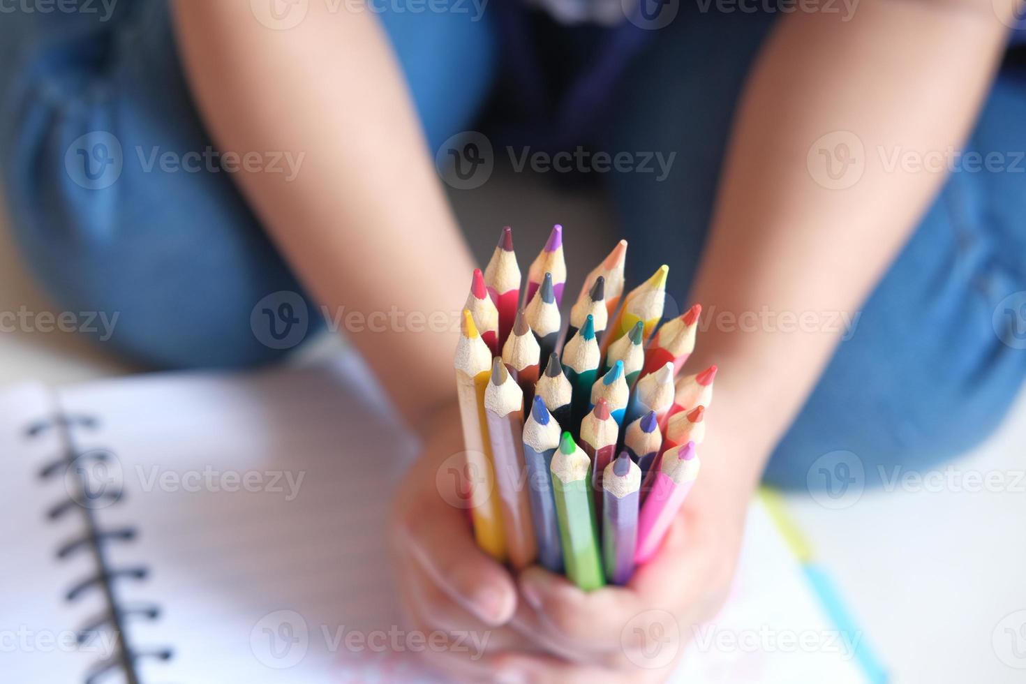 Gros plan de la main d'un enfant tenant de nombreux crayons colorés photo