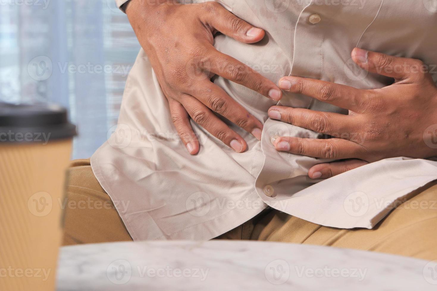 Homme souffrant de douleurs à l'estomac assis sur un canapé photo