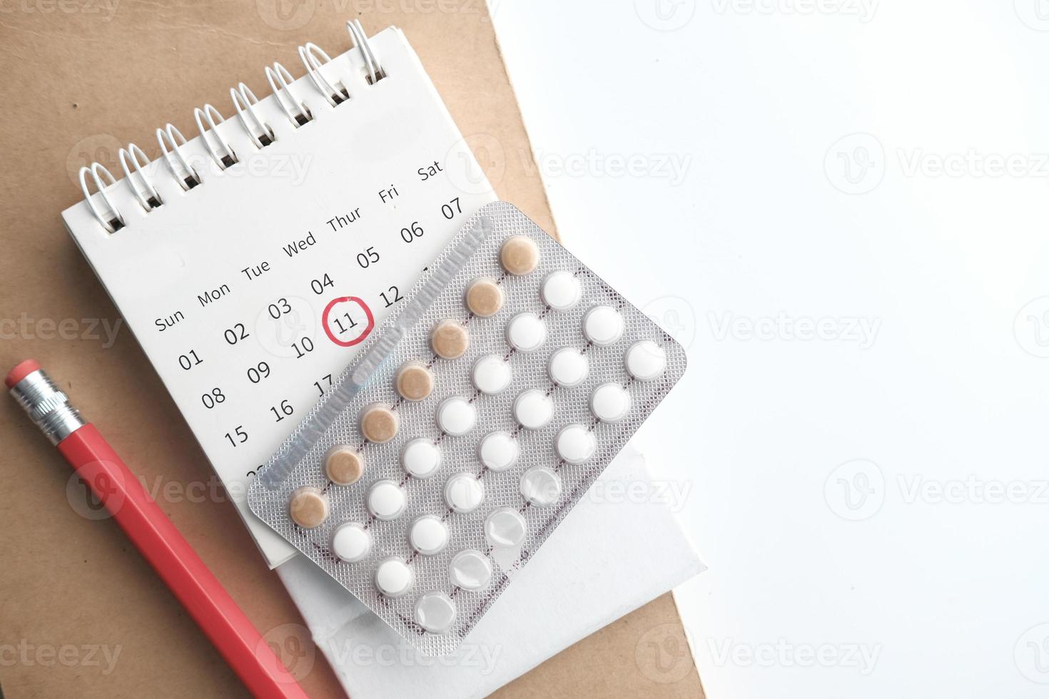 pilules contraceptives, calendrier et bloc-notes sur table photo