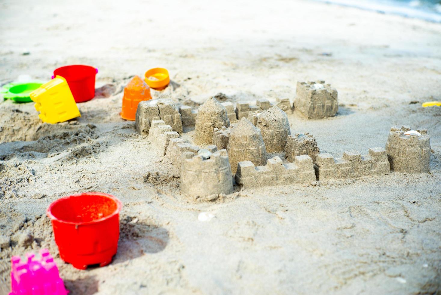 le château de sable construit en utilisant les moules en plastique sur la plage photo