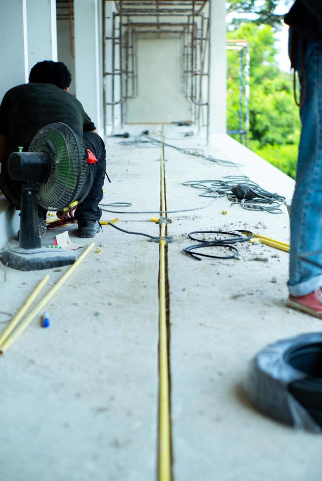 travailleurs installant le fil électrique et le tuyau dans la maison en construction photo