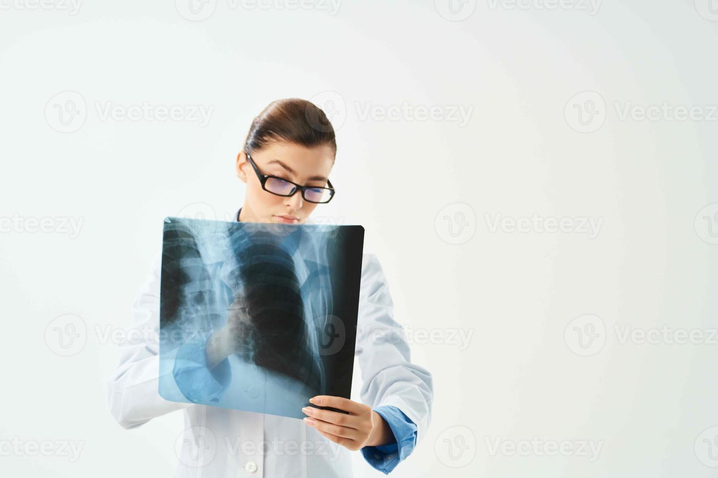 une infirmière dans une blanc manteau regards par une grossissant verre à un radiographie photo