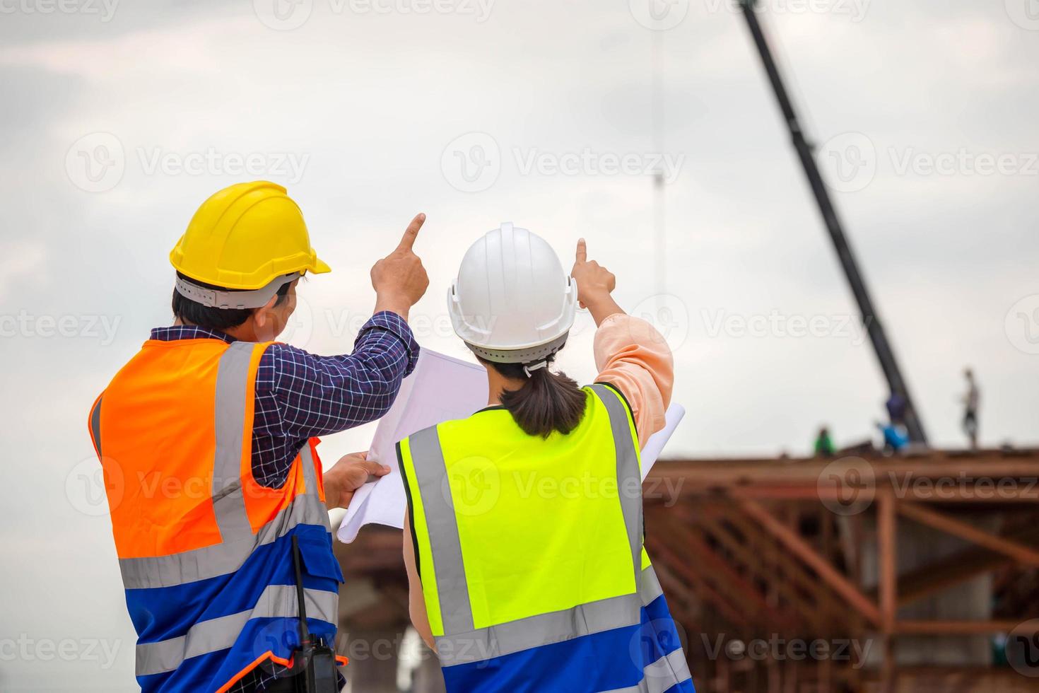 femelle ingénieur et contremaître ouvrier vérification projet à bâtiment placer, ingénieur et constructeurs dans casques discuter sur construction placer, travail en équipe concepts photo