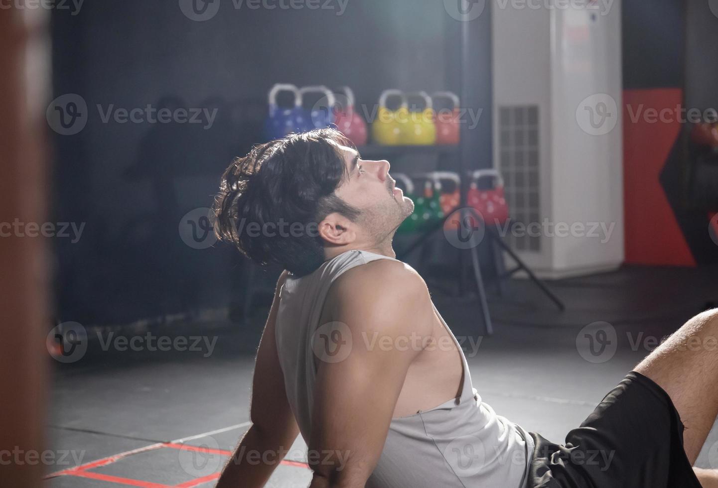 fatigué homme dans aptitude salle de sport, Jeune sportif séance sur le sol de le salle de sport, sport et aptitude concepts photo