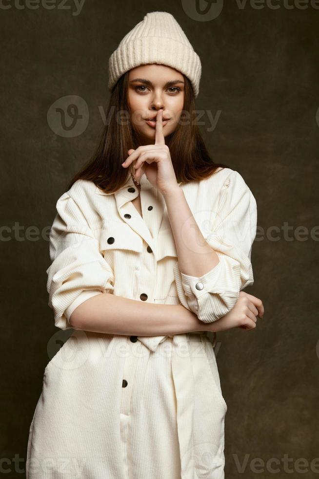 femme octobre casquettes en portant une doigt près lèvres et lumière combinaison foncé Contexte photo