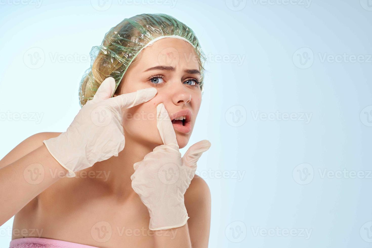 femme dans douche casquette serre boutons sur sa visage avec gants photo
