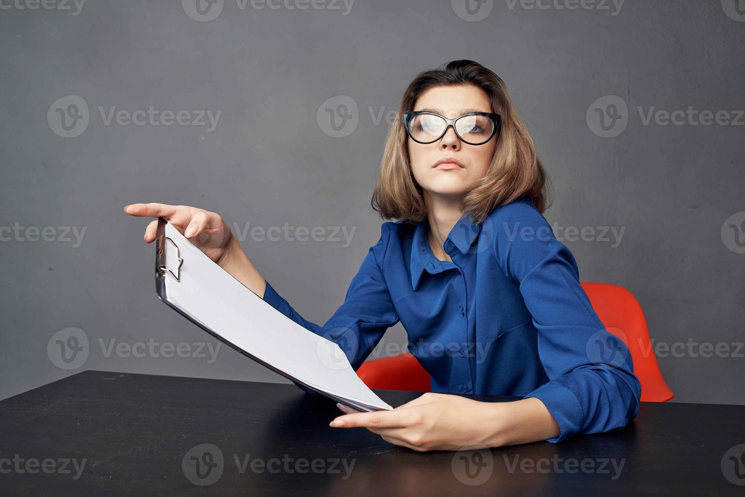 affaires femme dans bleu chemise est assis à le table dossier dans mains les documents photo