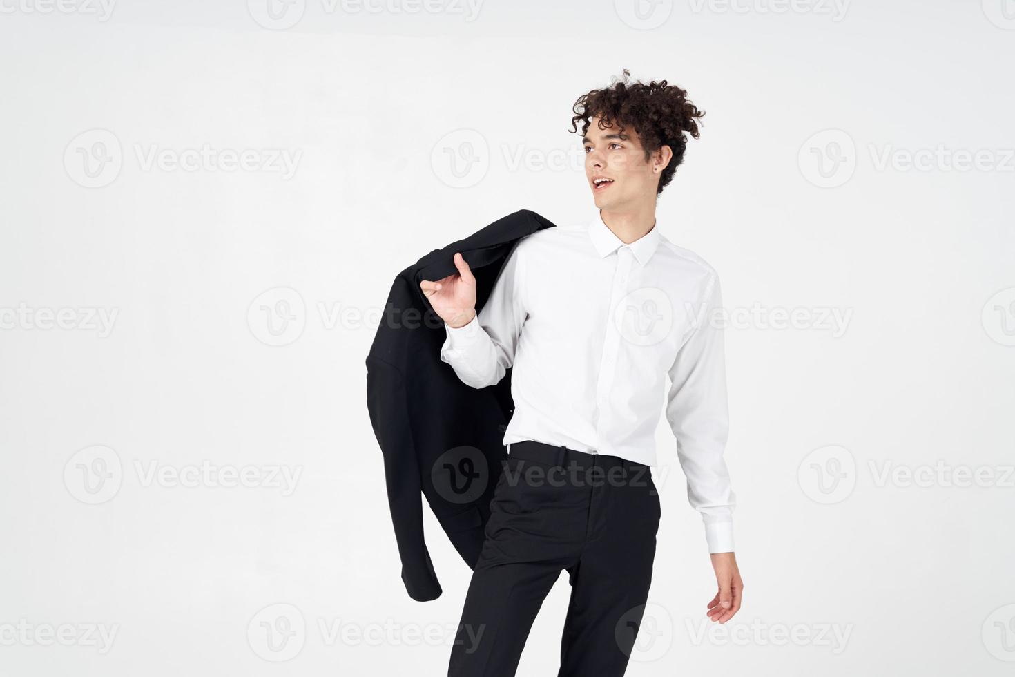 homme avec frisé cheveux et dans une classique costume détient une veste dans le sien main mode style photo