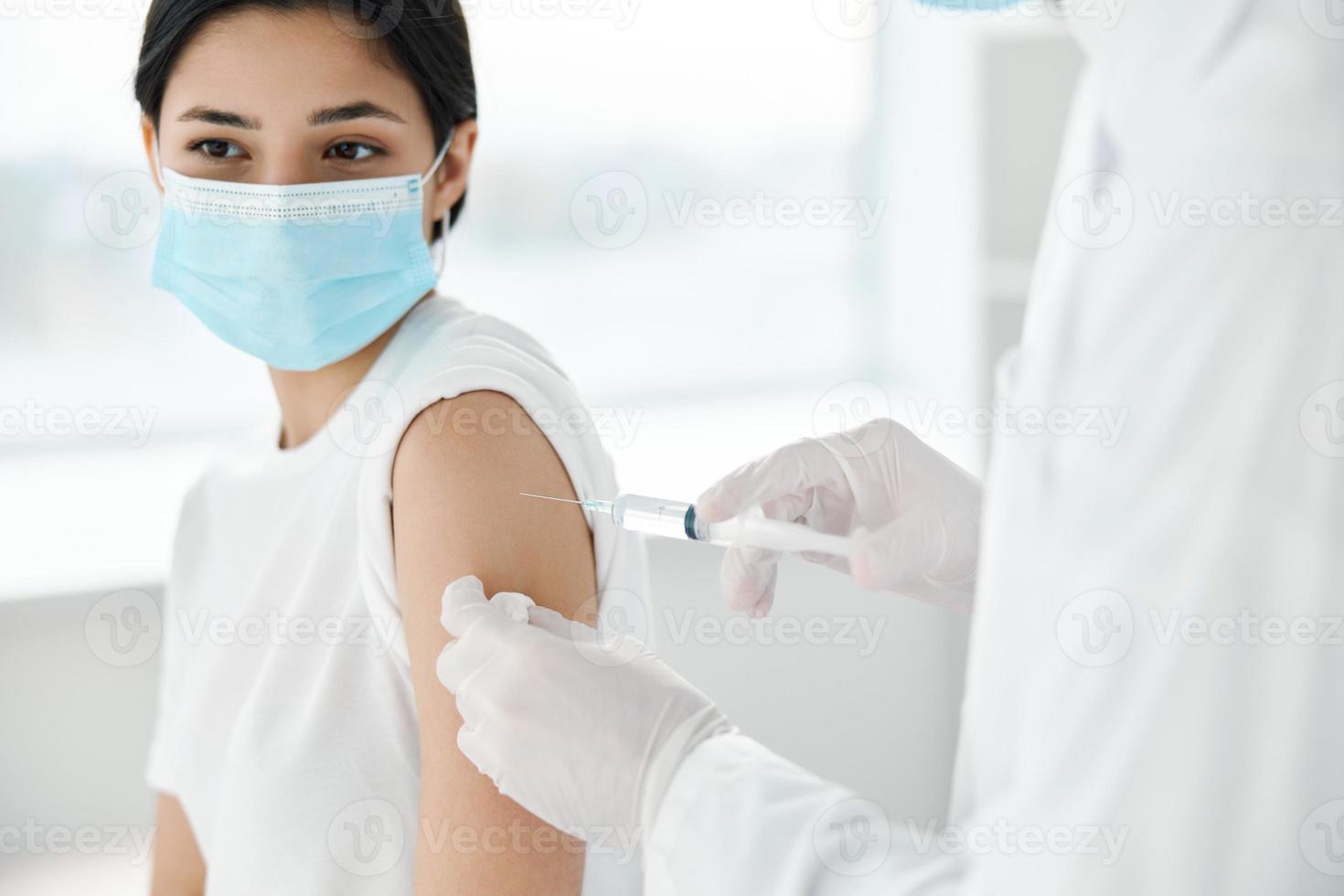 médecin dans protecteur gants fait du un injection dans le épaule femme dans une médical masque convoitise vaccination photo