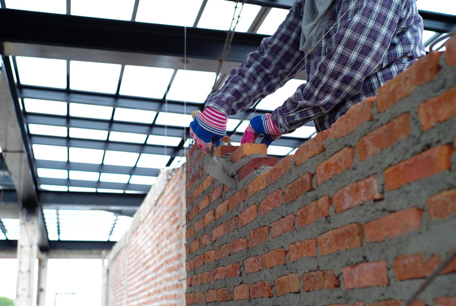 Gros plan des mains de travailleur installant les maçons pour la construction du mur sur le chantier de construction photo