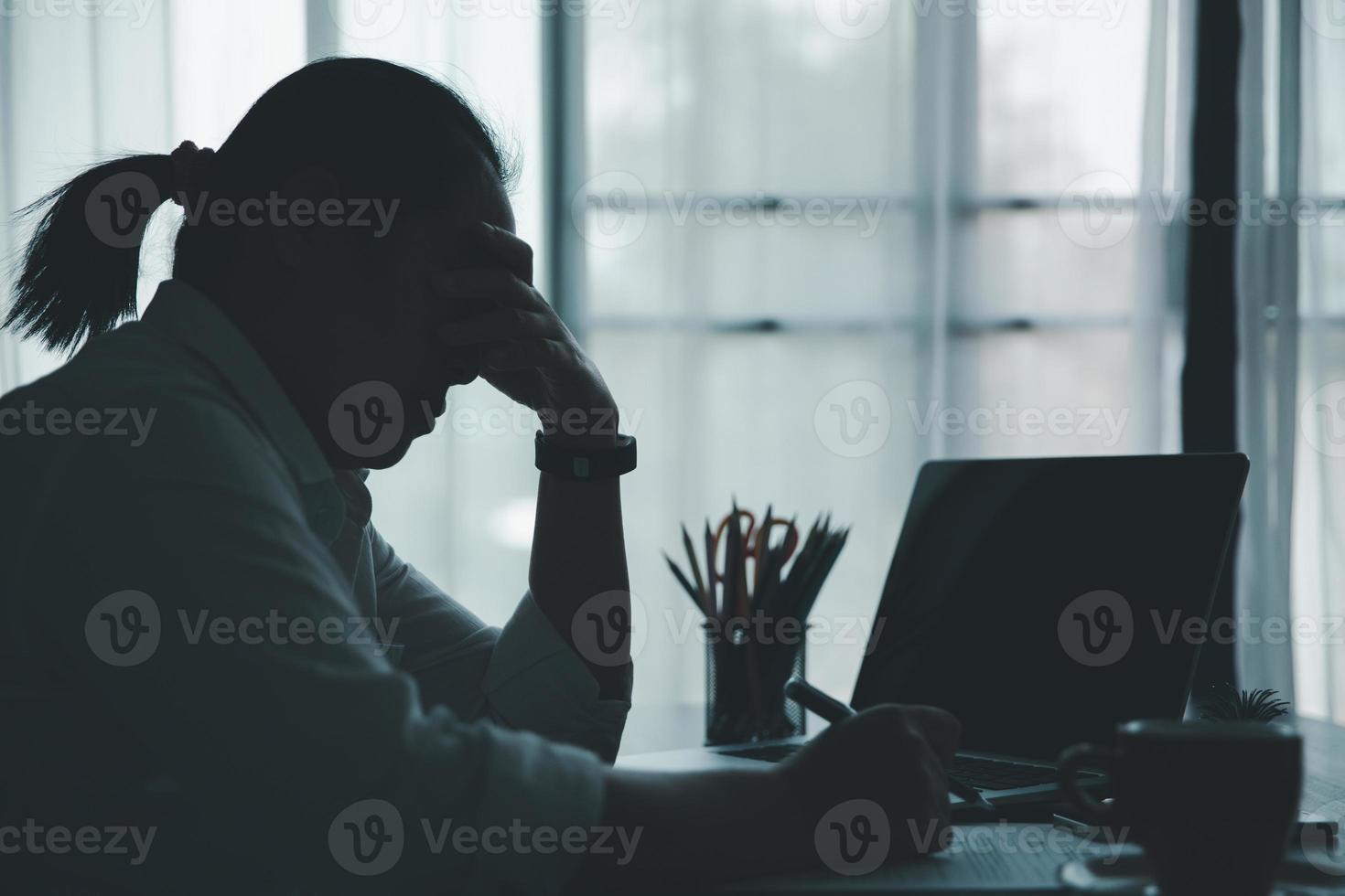 stress femme d'affaires personne de travail acharné, dépression au bureau. une employée fatiguée et anxieuse mécontente du travail problématique. jeune femme d'affaires triste assise devant un ordinateur portable sur le bureau. photo