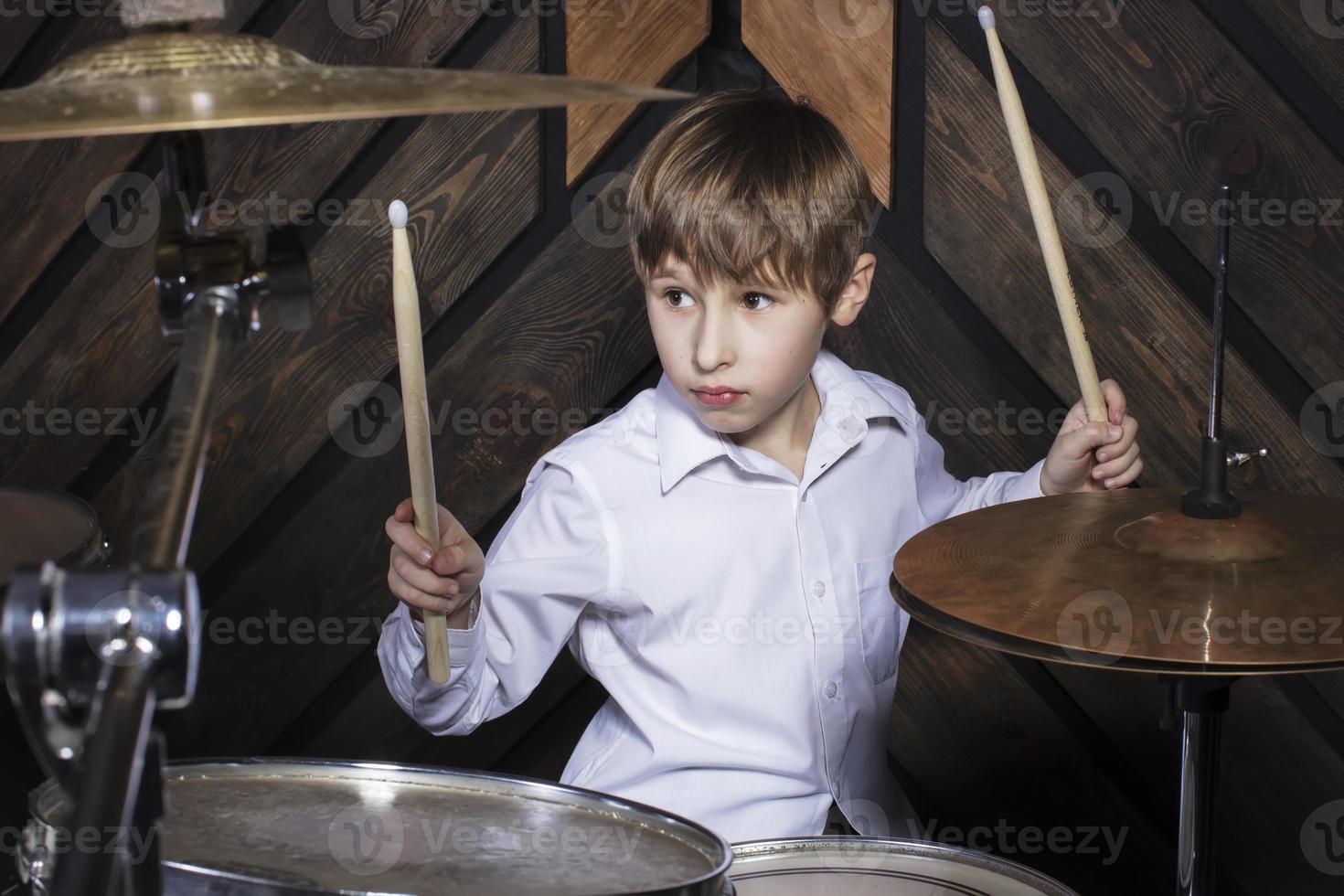 le enfant pièces le tambours. garçon musicien derrière une tambour trousse. photo