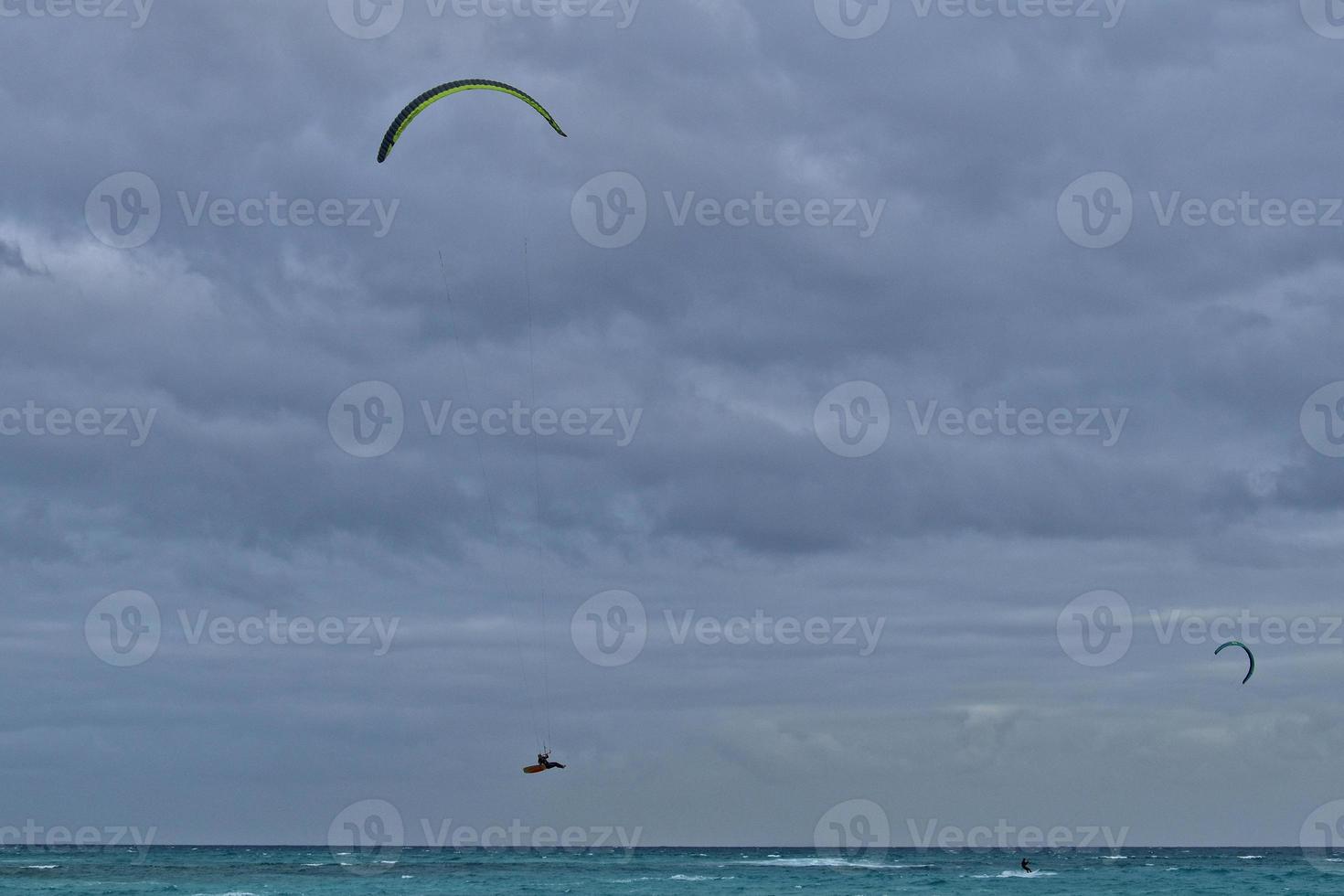 été paysage avec le océan avec foncé nuageux vagues et surfeurmi trousse avec parachutes flottant sur le rive photo