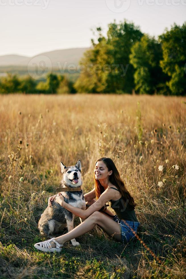 femme séance dans champ avec teckel chien souriant tandis que dépenses temps dans la nature avec ami chien dans l'automne à le coucher du soleil tandis que en voyageant photo