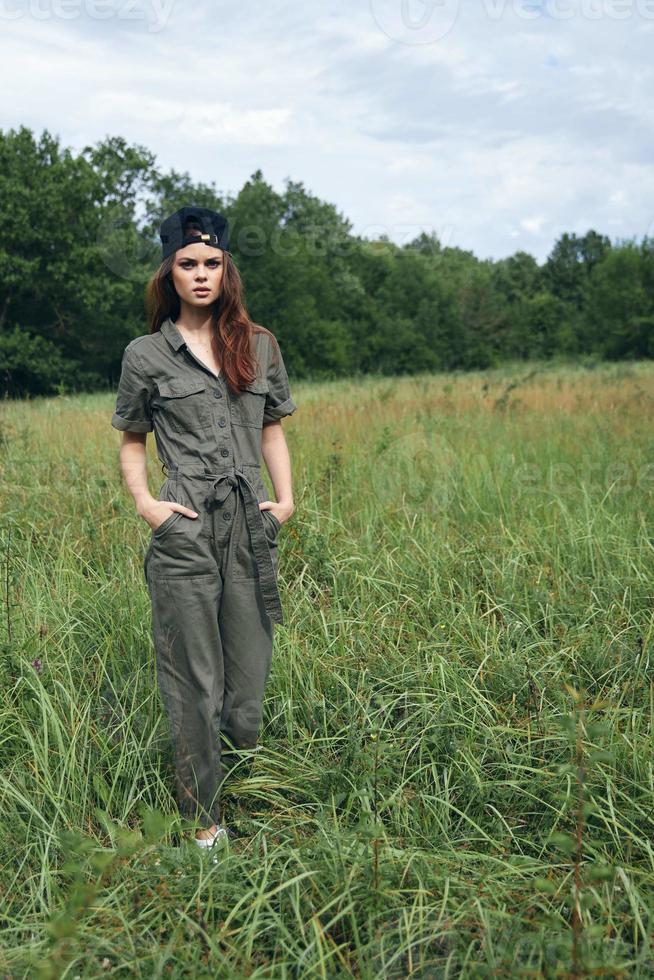 femme dans le Prairie marcher votre mains dans le les poches de vert photo