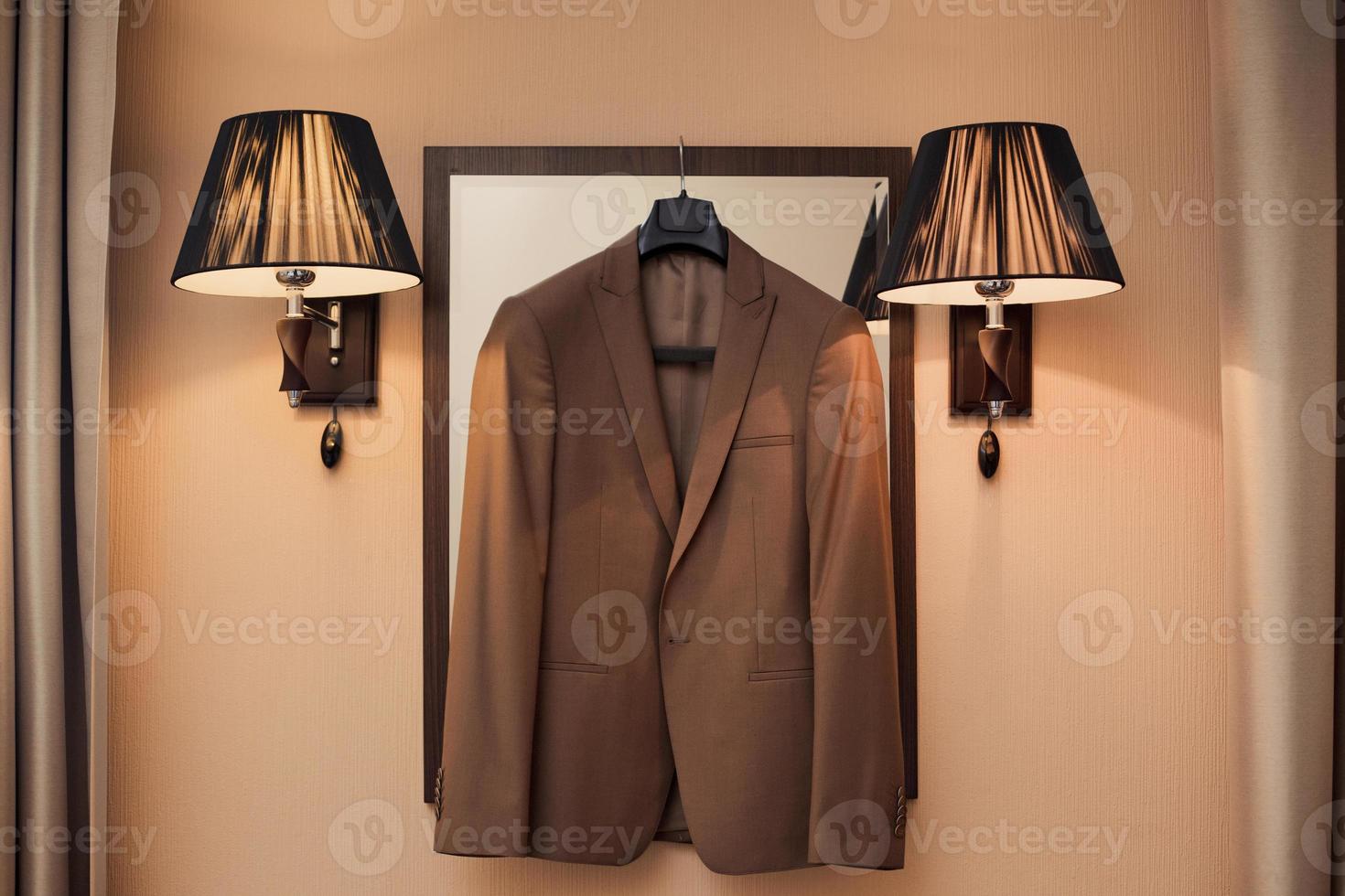 en train de préparer pour un soir un événement dans formel porter. Pour des hommes marron costume veste sur une cintre dans le intérieur photo