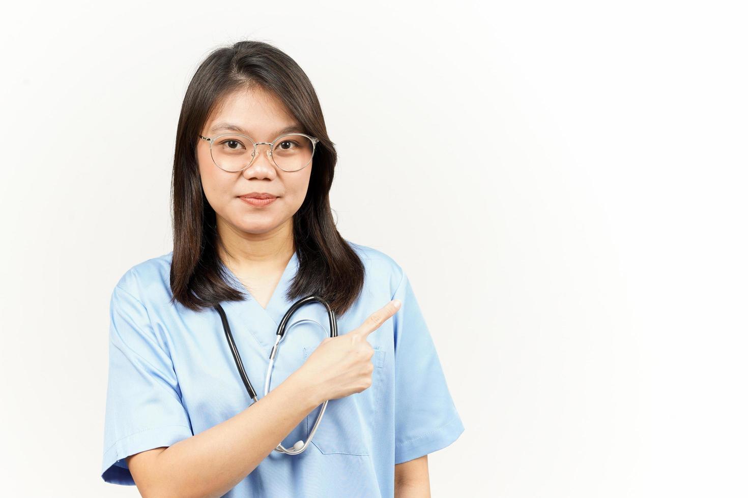 montrant produit et montrer du doigt côté de asiatique Jeune médecin isolé sur blanc Contexte photo