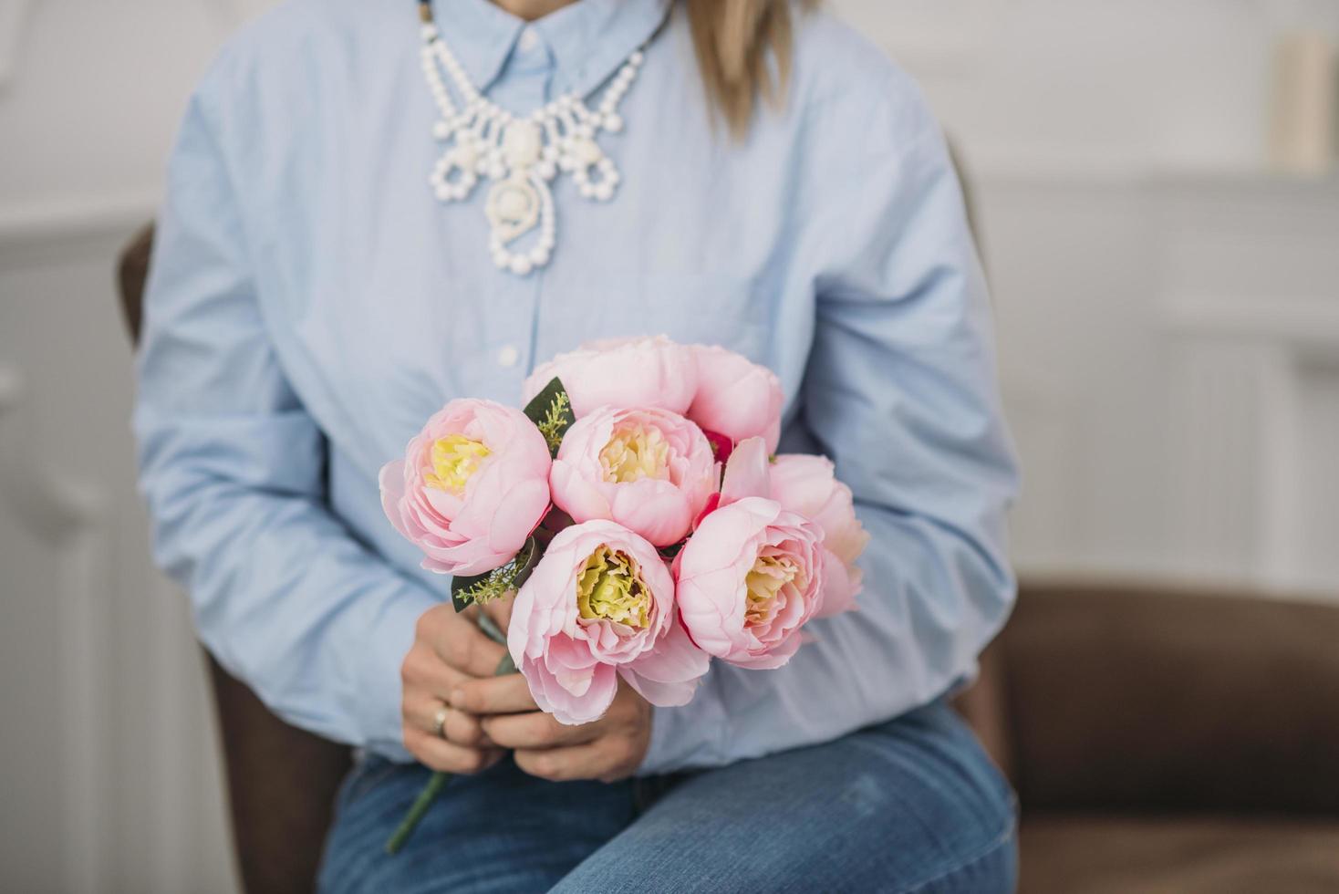 femme en bleu tenant des pivoines roses photo