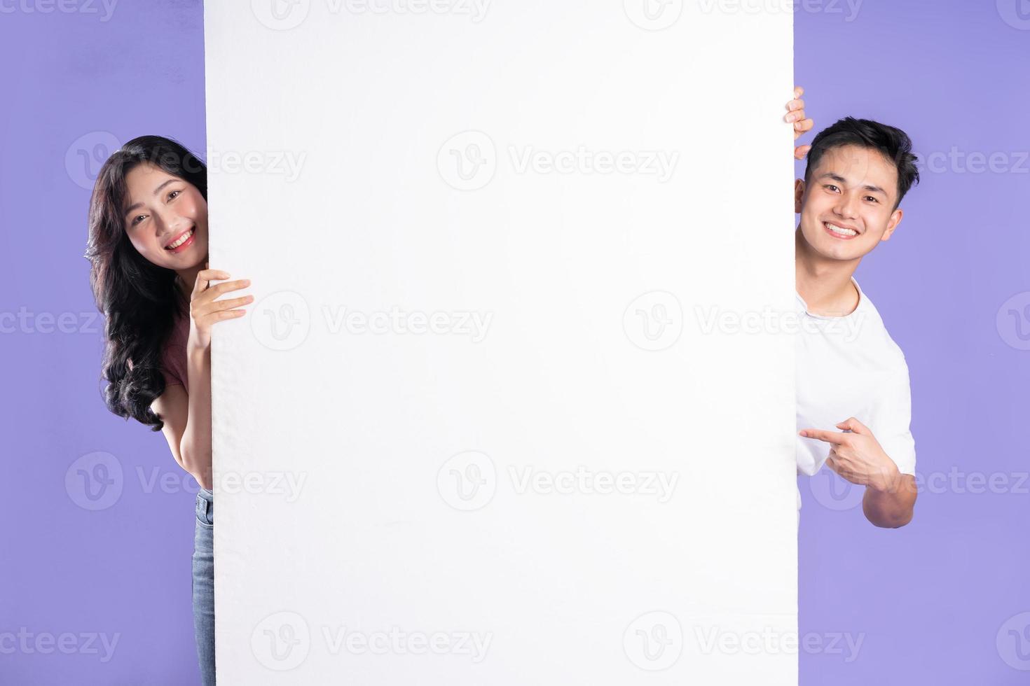 image de asiatique couple posant suivant à panneau d'affichage, isolé sur violet Contexte photo