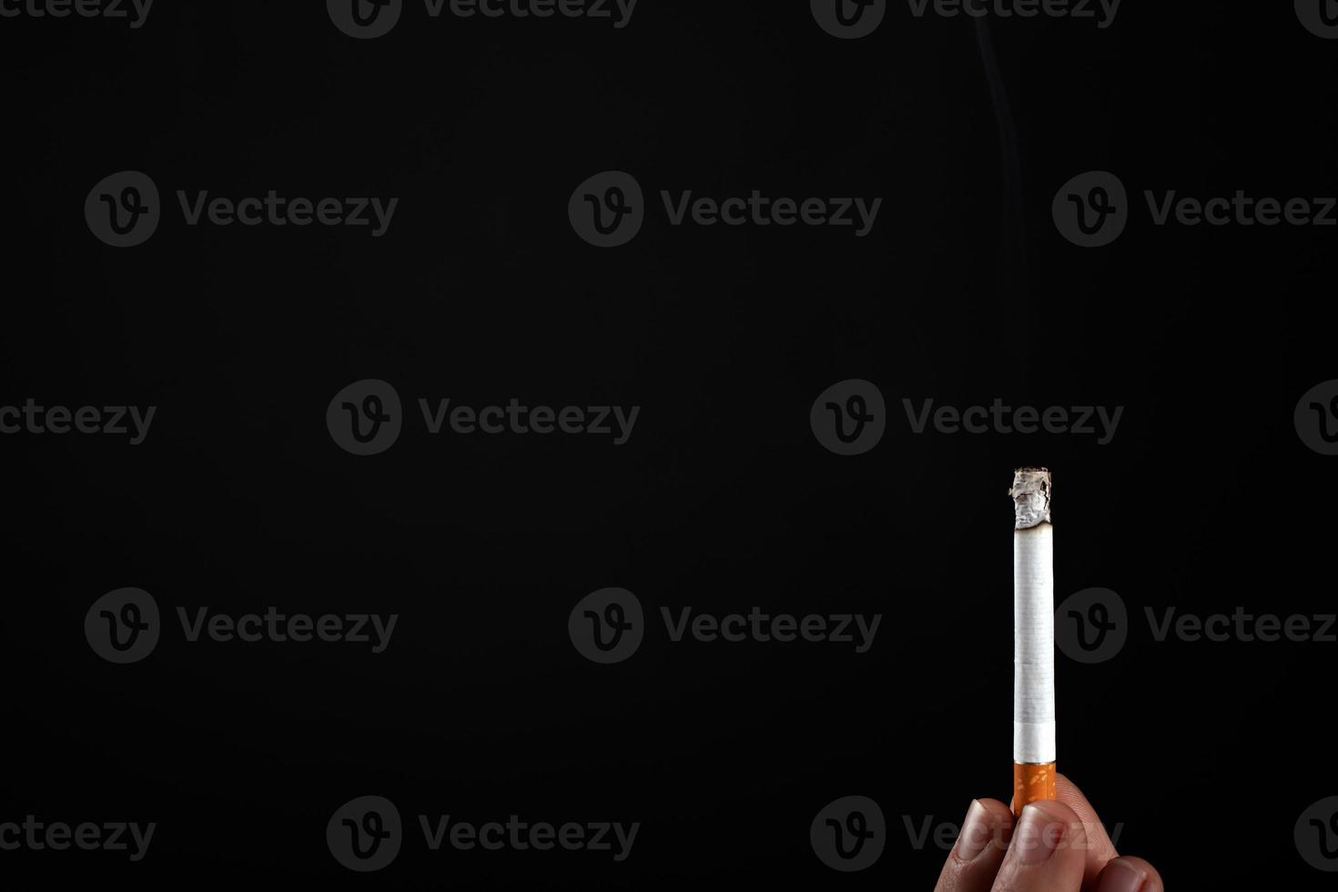 cigarette allumée à la main sur un fond noir avec copie espace photo