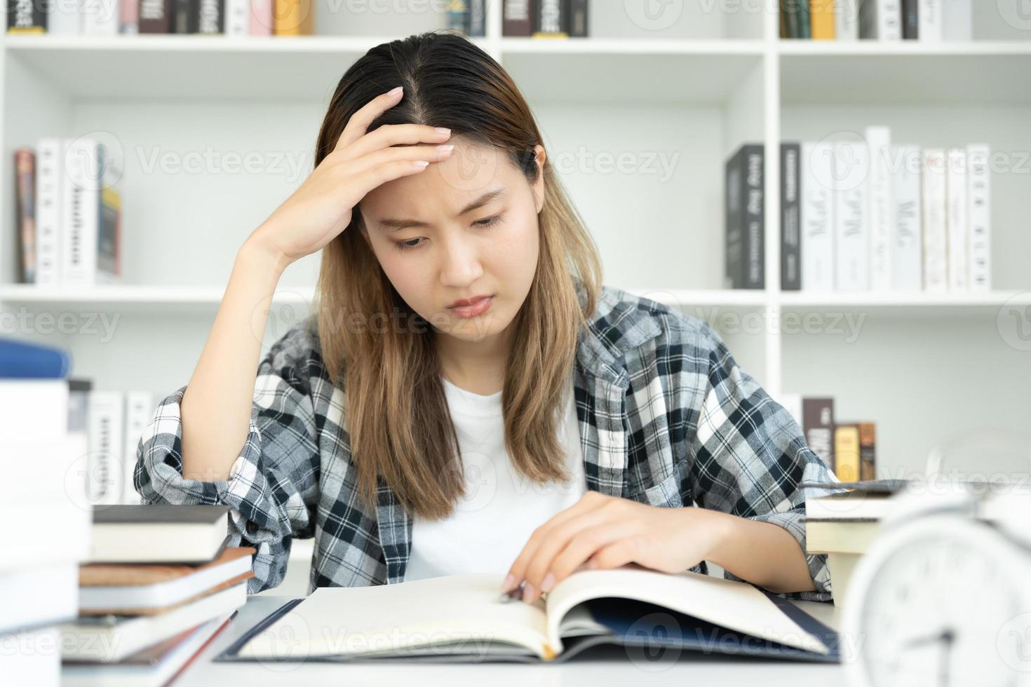 une étudiante asiatique a de l'anxiété à cause des examens, les femmes se préparent aux tests et apprennent les leçons à la bibliothèque. stress, désespoir, hâte, incompréhension lecture, découragement, attente, connaissance photo