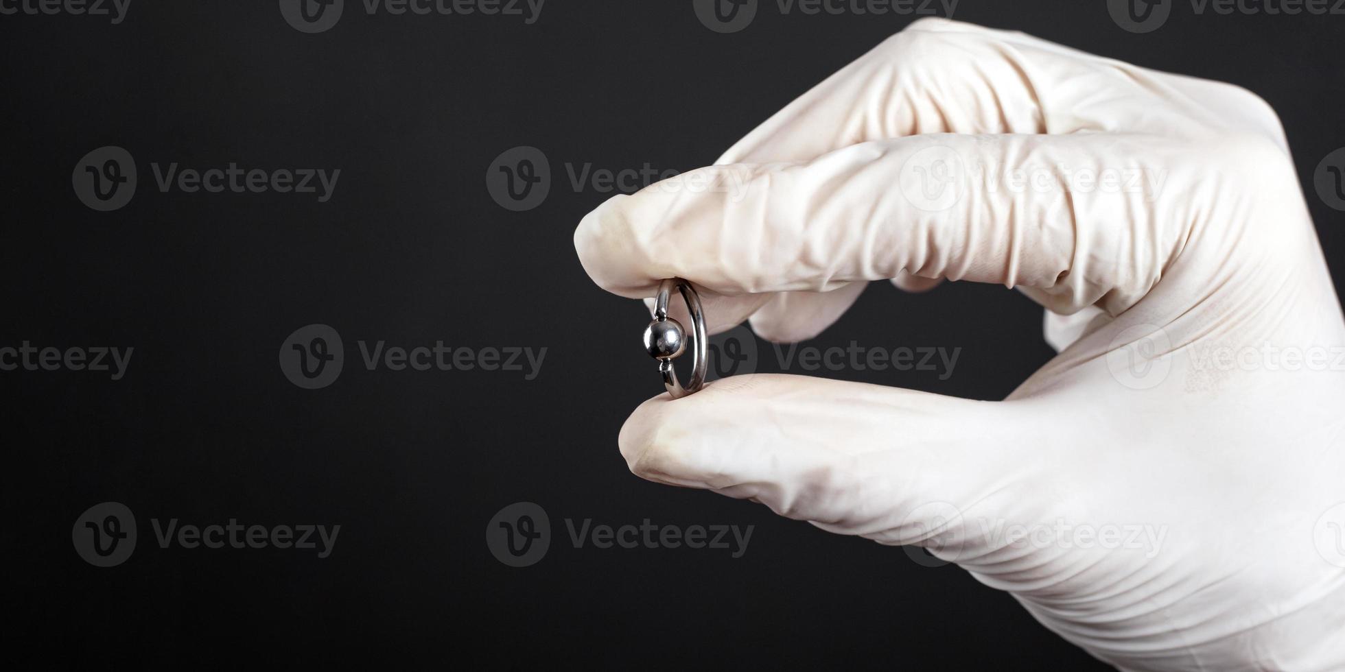 Bijoux bague piercing en argent à la main sur fond sombre close-up photo