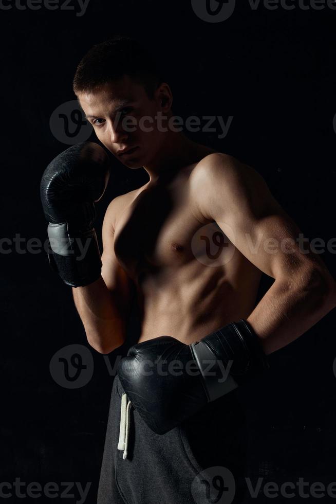 boxeur dans noir gants sur une foncé Contexte gonflé torse photo