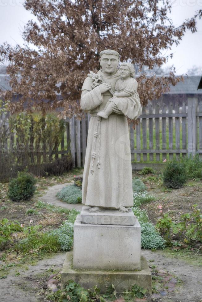 marbre figure de une Christian Saint avec Jésus sur le sien main sur une gris triste l'automne journée photo