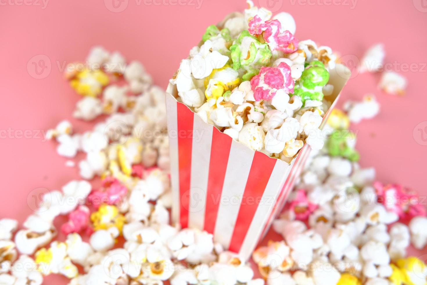 Pop-corn renversé d'un récipient sur fond rouge photo