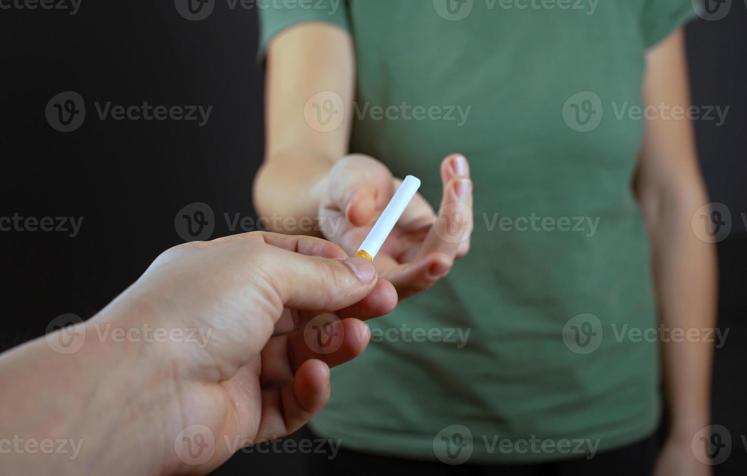 mec donne une cigarette à la fille sur un fond sombre photo