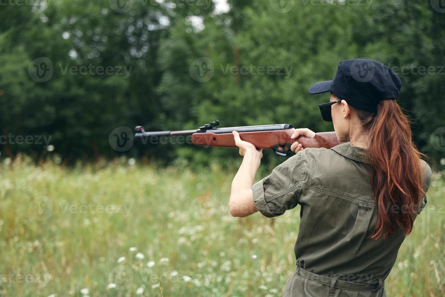 femme soldat arrière vue de une femme chasses avec une fusil à pompe des lunettes de soleil noir casquette photo