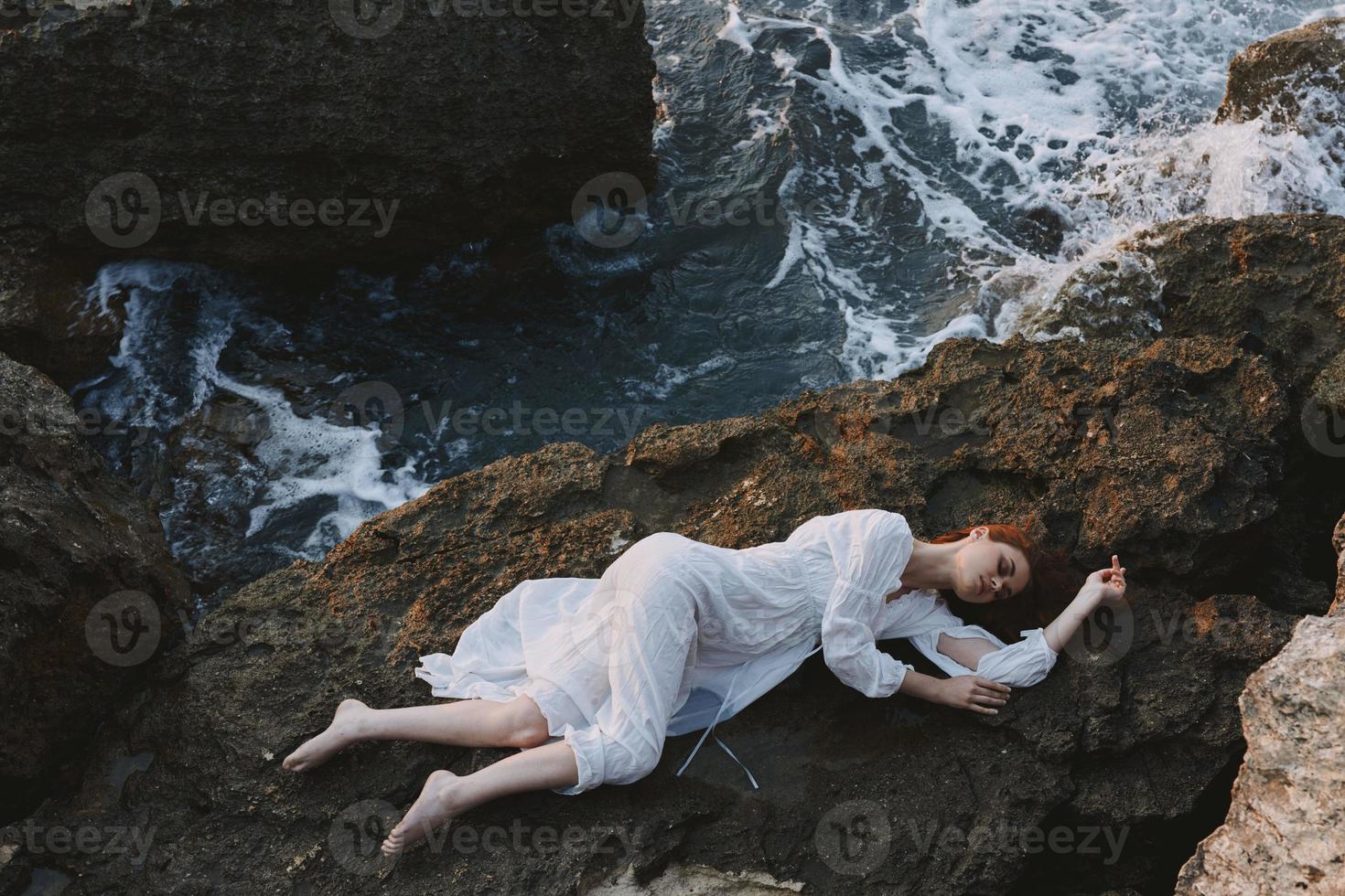 sensuel femme mensonge sur rocheux côte avec des fissures sur rocheux surface paysage photo