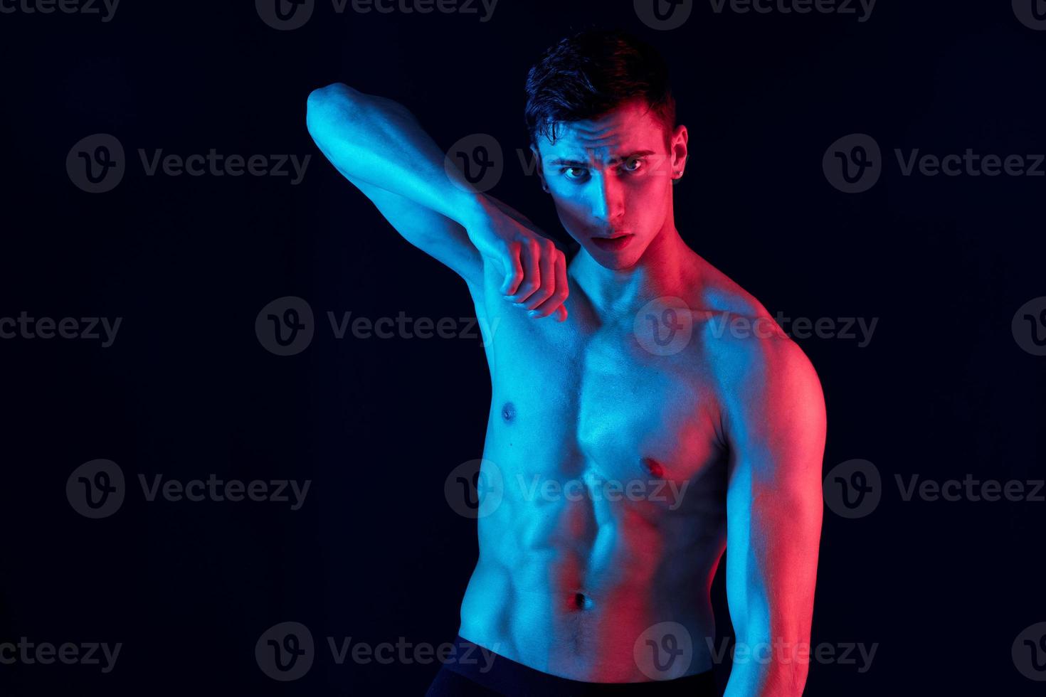 Masculin athlète avec pompé en haut muscles et une torse sur une noir Contexte photo