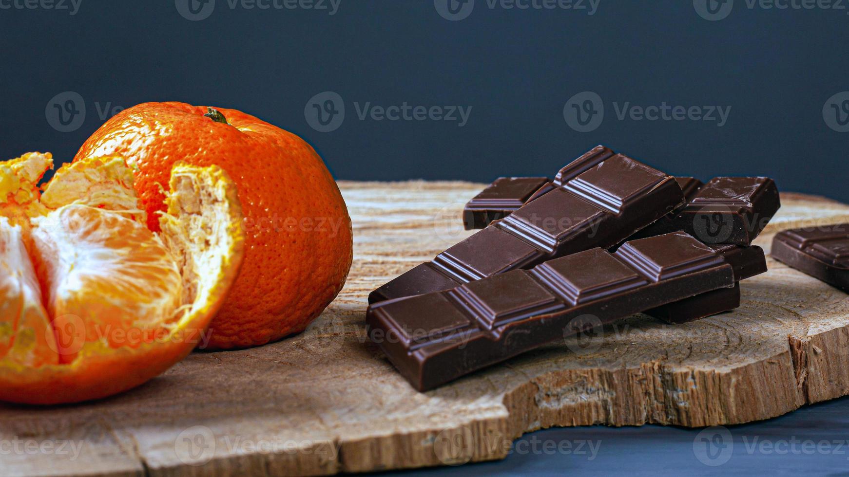 chocolat et mandarines sur planche de bois et fond sombre photo