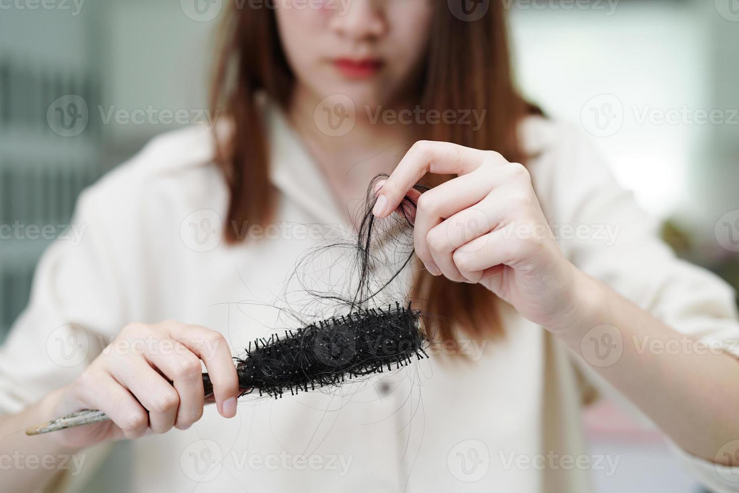 une femme asiatique a un problème avec la perte de cheveux longs attachée dans sa main. photo