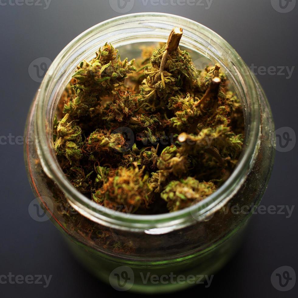 bocal en verre avec des bourgeons de cannabis séchés photo
