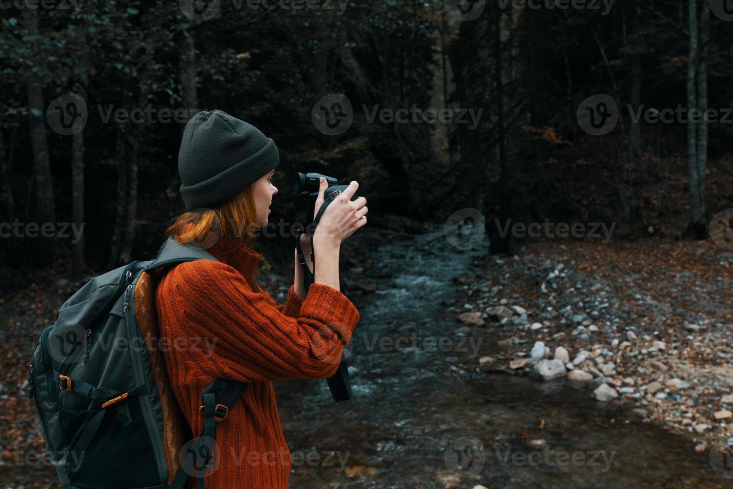 femme avec une caméra près une étang dans le montagnes sur la nature et des arbres forêt paysage photo