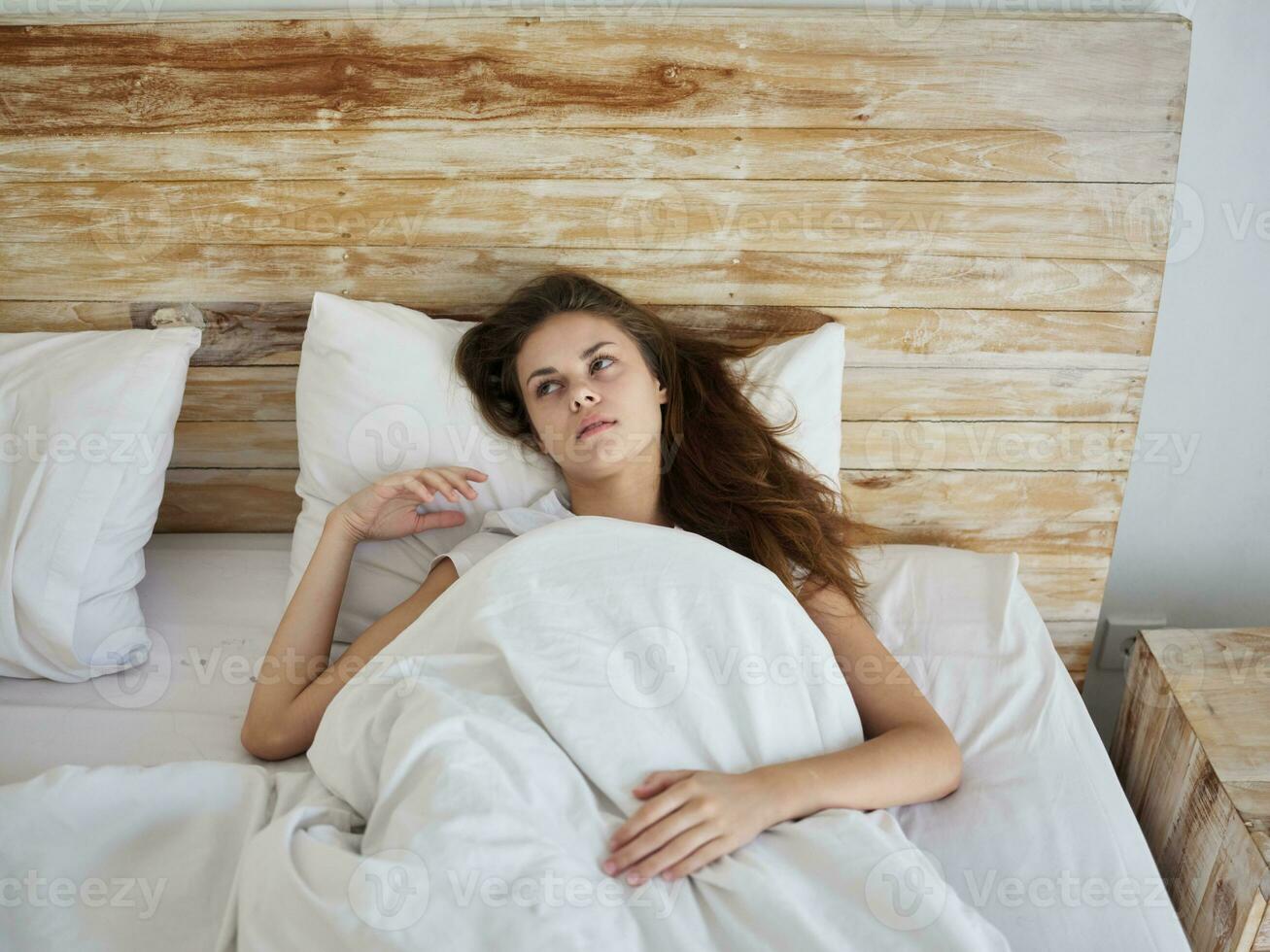femme mensonges dans lit en dessous de le couverture dans le Matin relaxation émotions photo