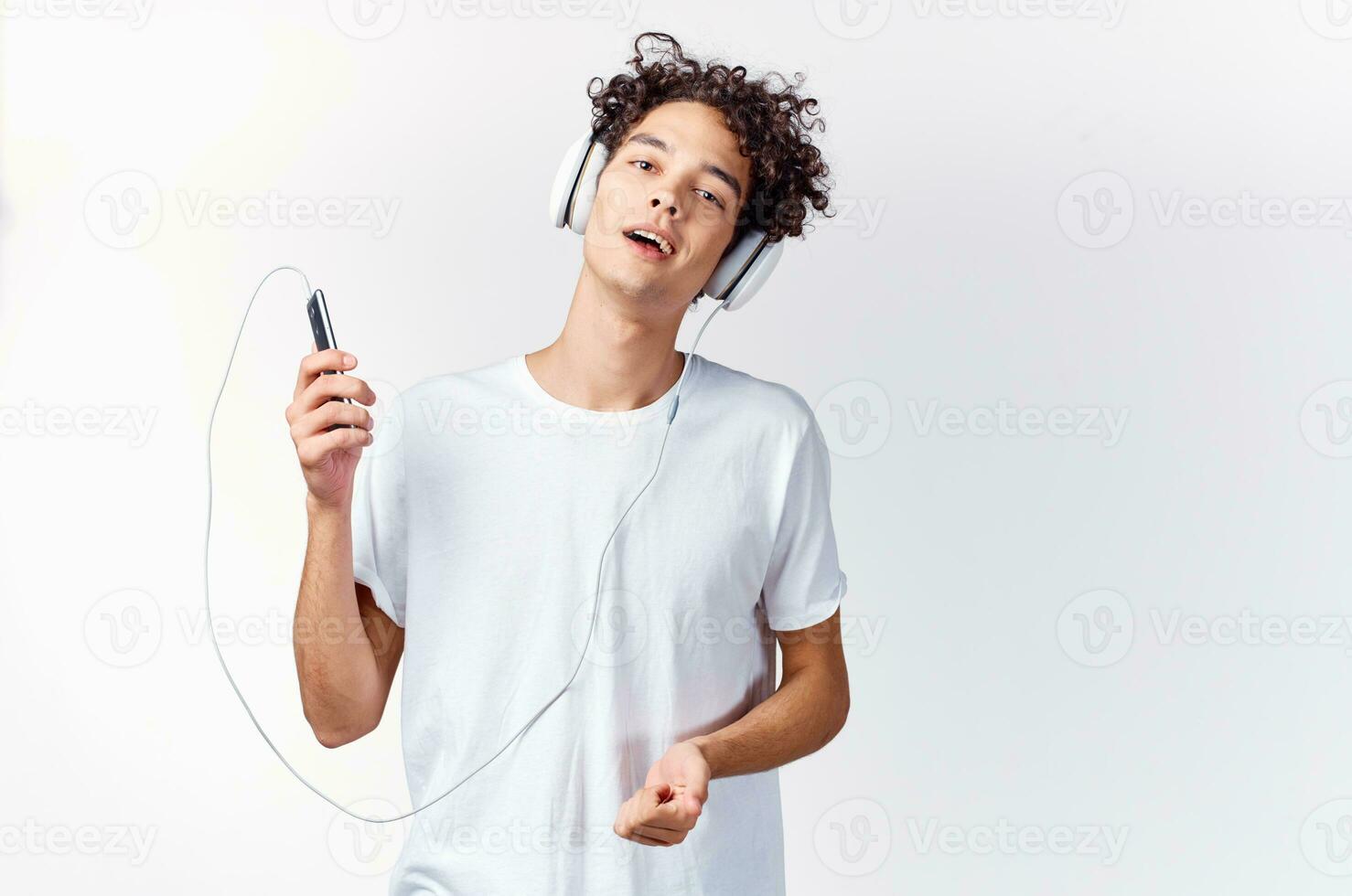 émotif homme dans blanc T-shirt écoute à la musique avec écouteurs tondu vue photo