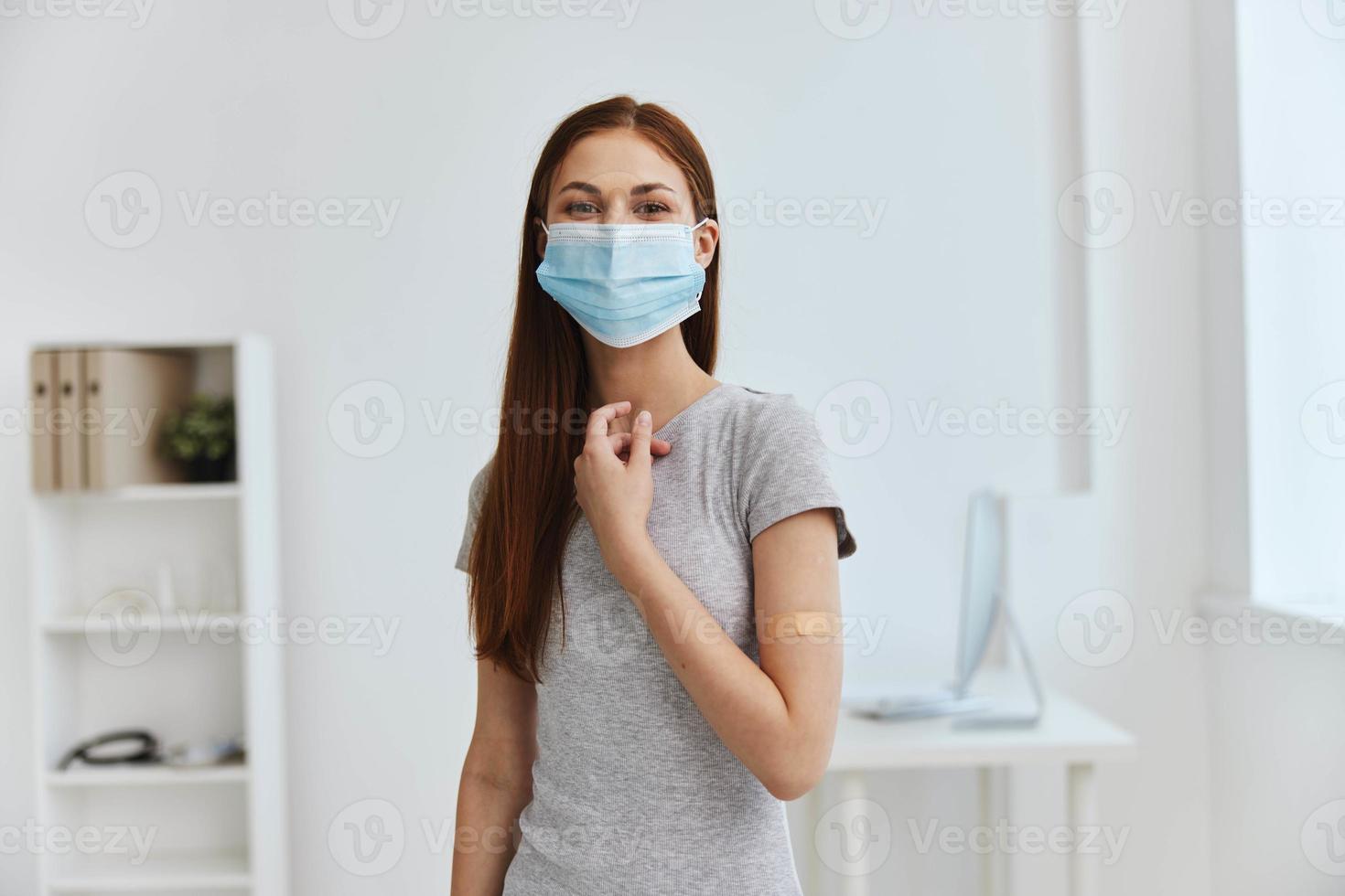 Jeune femme dans hôpital portant une médical masque avec une germicide pièce sur sa épaule sécurité immunisation photo