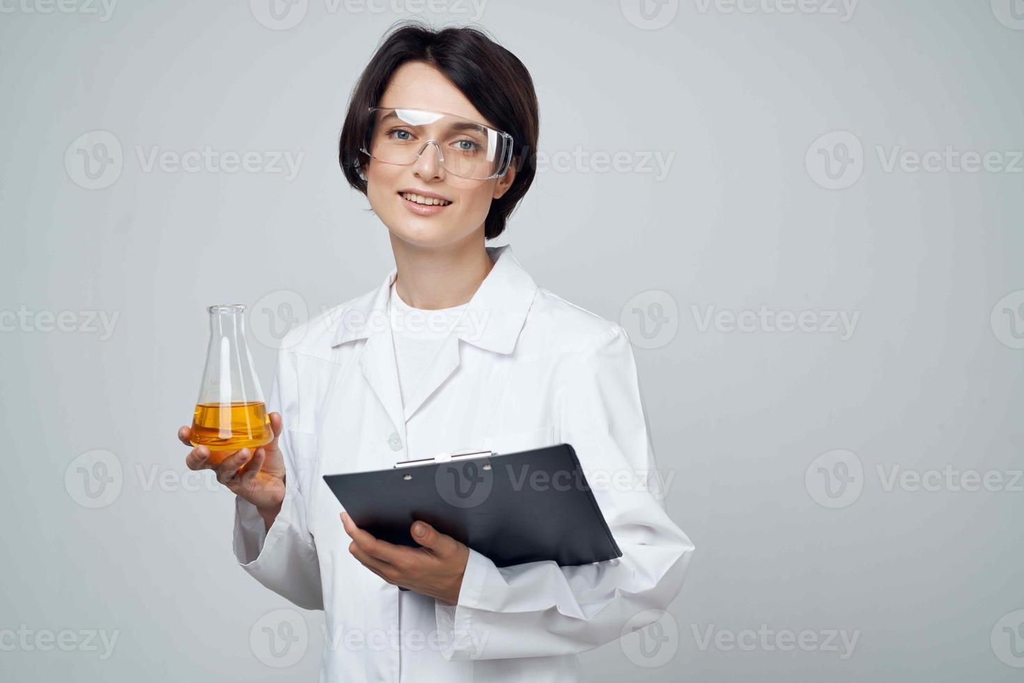 femelle laboratoire assistant dans une blanc manteau tester tube avec une chimique Solution une analyse photo