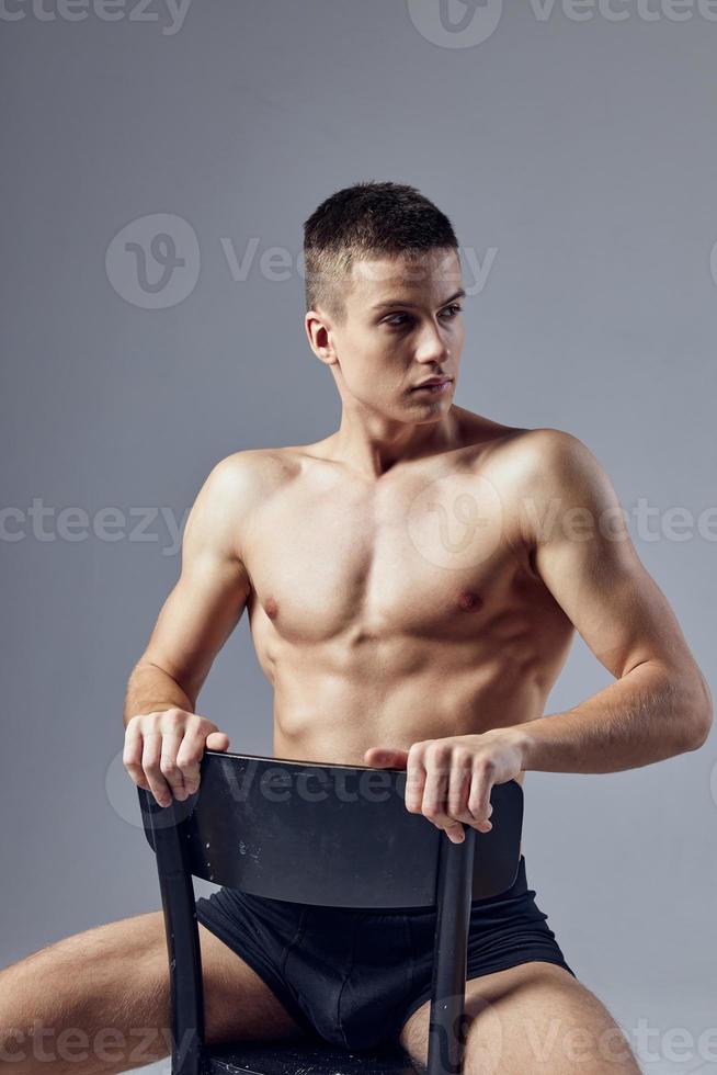 athlétique homme dans noir culotte pompé en haut corps est assis sur une chaise photo