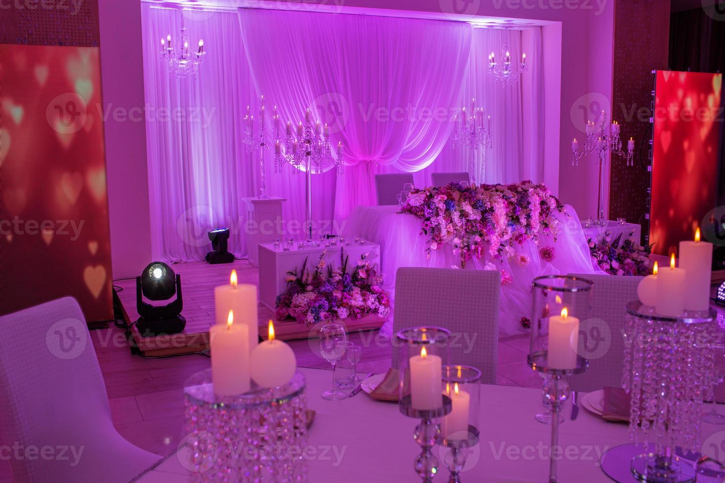 table de fête décorée de fleurs, de tissus et de chandeliers. décoration de mariage de luxe avec des lumières violettes. photo