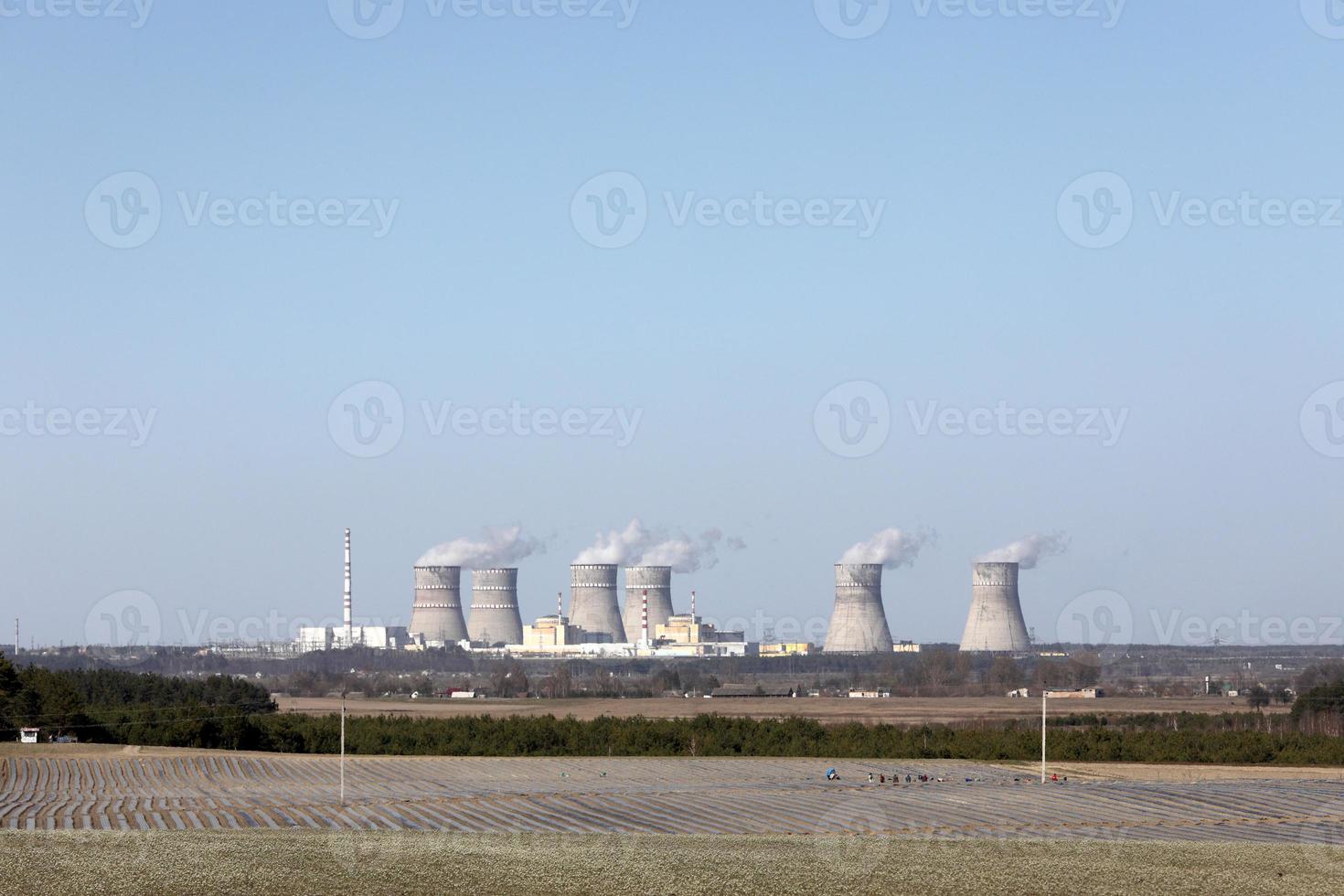 vue d'une centrale nucléaire. vue sur les cheminées fumantes d'une centrale nucléaire, les lignes électriques et la forêt, sous un ciel bleu avec des nuages blancs. photo