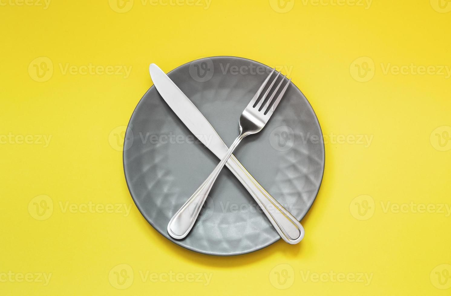 Assiette grise vide et couverts sur fond jaune photo