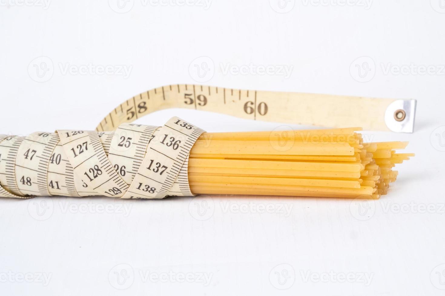 bouquet de brut spaghetti lié avec une mesure ruban sur une blanc Contexte photo